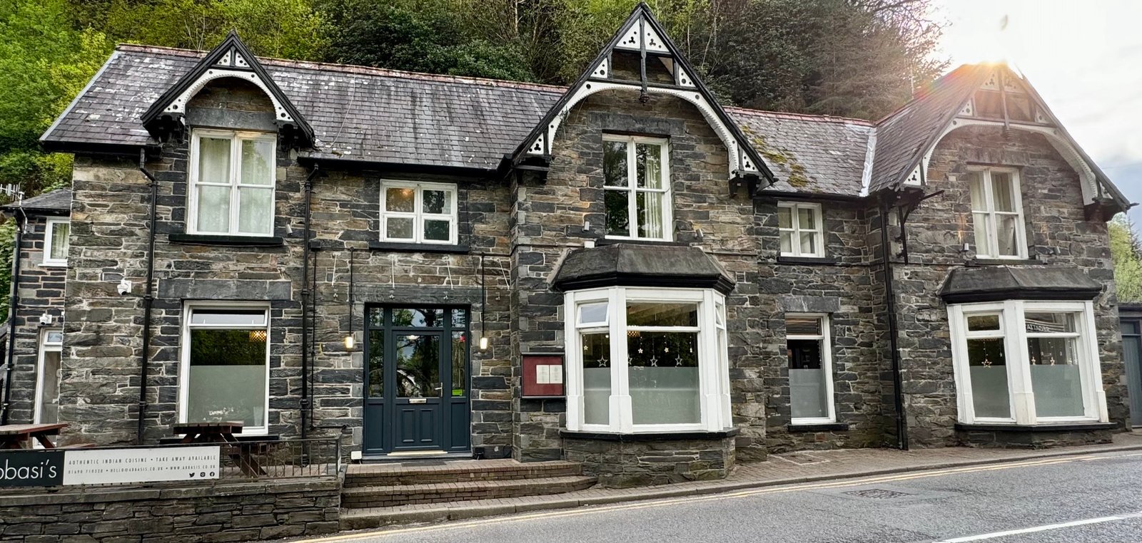 Abbasi's stone restaurant on Holyhead Road, wrapped in the wooded hills of Betws-y-Coed at dusk